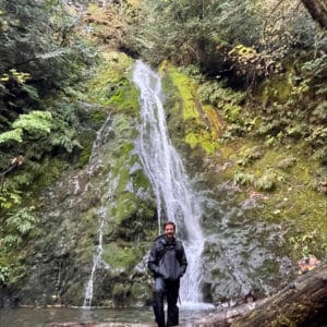 Josh Pelkey at a waterfall. Josh is an expedition and luxury cruise travel advisor at Q Cruise + Travel Chicago. 