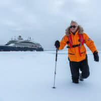 Rob Clabbers of Q Cruise + Travel explores the North Pole with Ponant Le Commandant Charcot in the background at 90 degrees north
