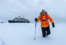 Rob Clabbers of Q Cruise + Travel explores the North Pole with Ponant Le Commandant Charcot in the background at 90 degrees north